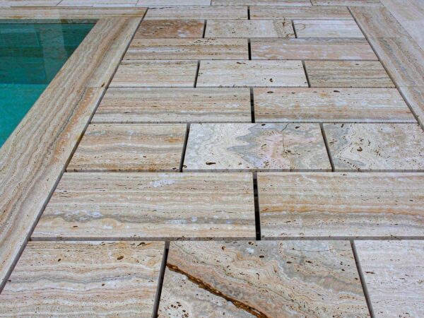 Travertine pool surround tile laid in a grid on a wet deck