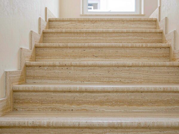 A travertine stair flight with solid slab risers and eased tread noses