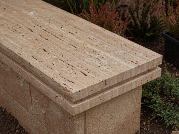 A travertine wall cap overhanging a rendered wall, drip groove underneath