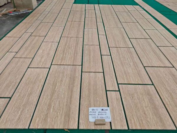 Long unfilled travertine slabs laid flat on a workshop floor, with a handwritten batch card resting on one