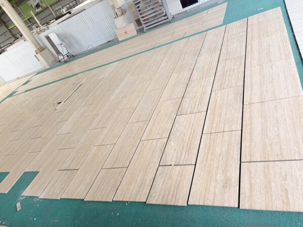 Travertine slabs sawn and laid out face up, showing the open vein-cut structure across the surface