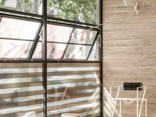 Travertine cladding wrapping an internal corner beside a steel-framed window