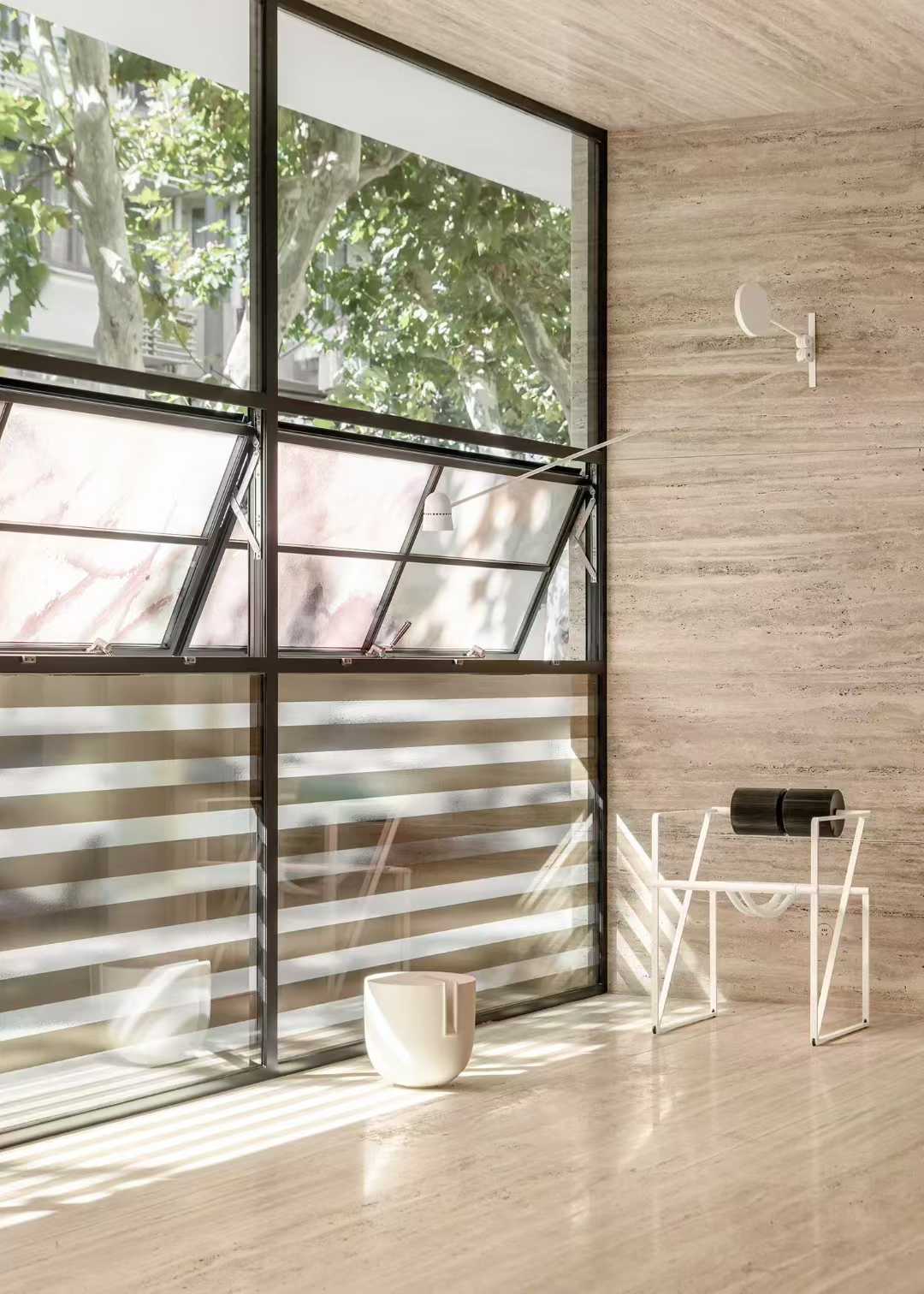 Travertine cladding wrapping an internal corner beside a steel-framed window