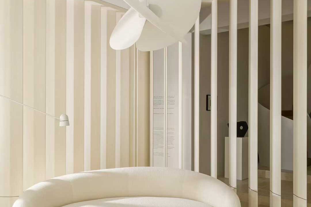 A pale interior with travertine on the floor and the wall beside a full-height window