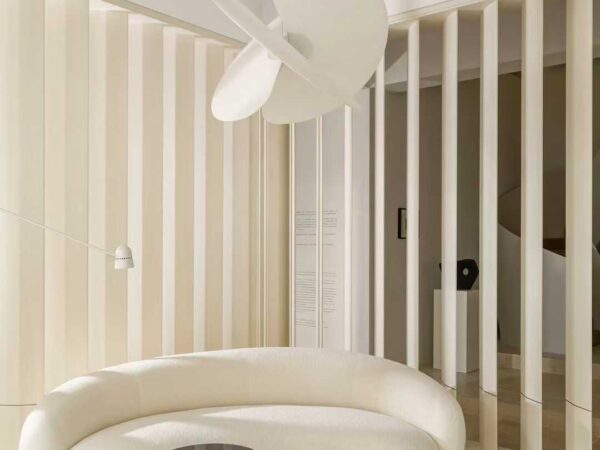 A pale interior with travertine on the floor and the wall beside a full-height window