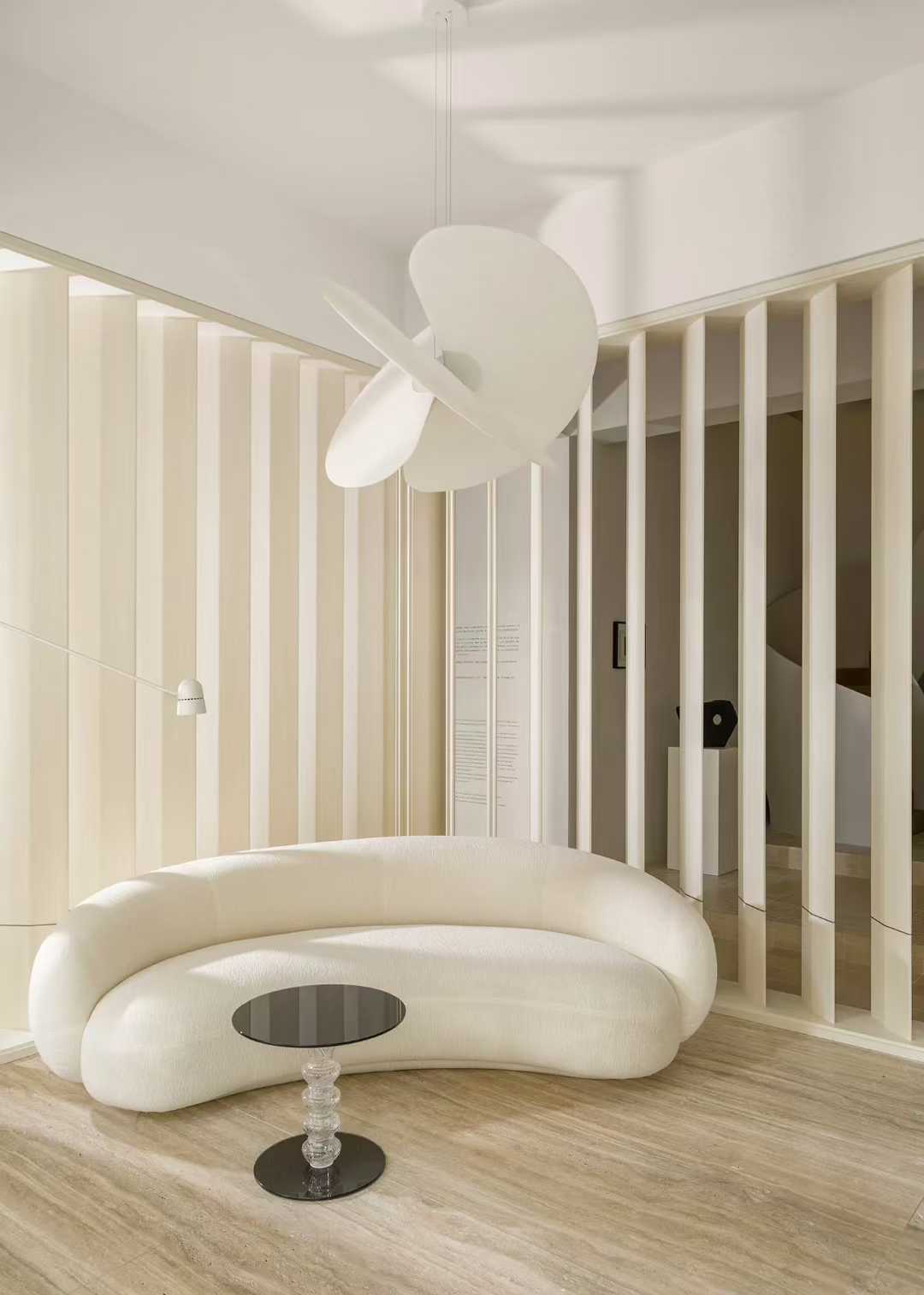 A pale interior with travertine on the floor and the wall beside a full-height window