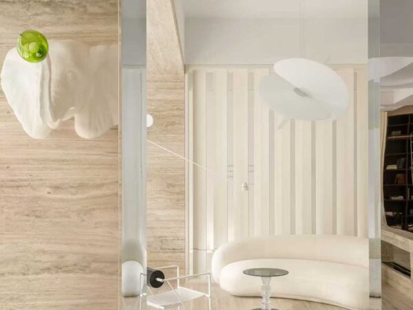 A travertine-clad column in a white interior with a curved bench and full-height glazing
