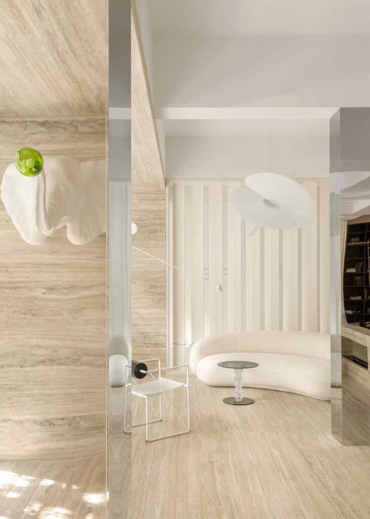 A travertine-clad column in a white interior with a curved bench and full-height glazing