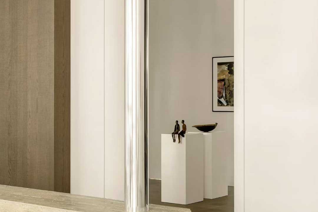 A travertine reception counter with a steel frame, in a white gallery interior