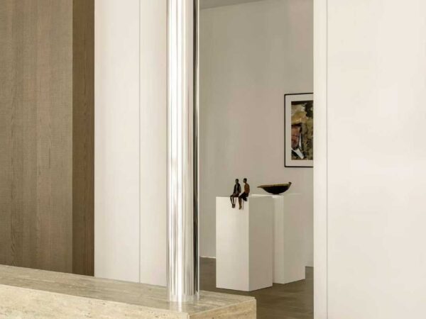 A travertine reception counter with a steel frame, in a white gallery interior