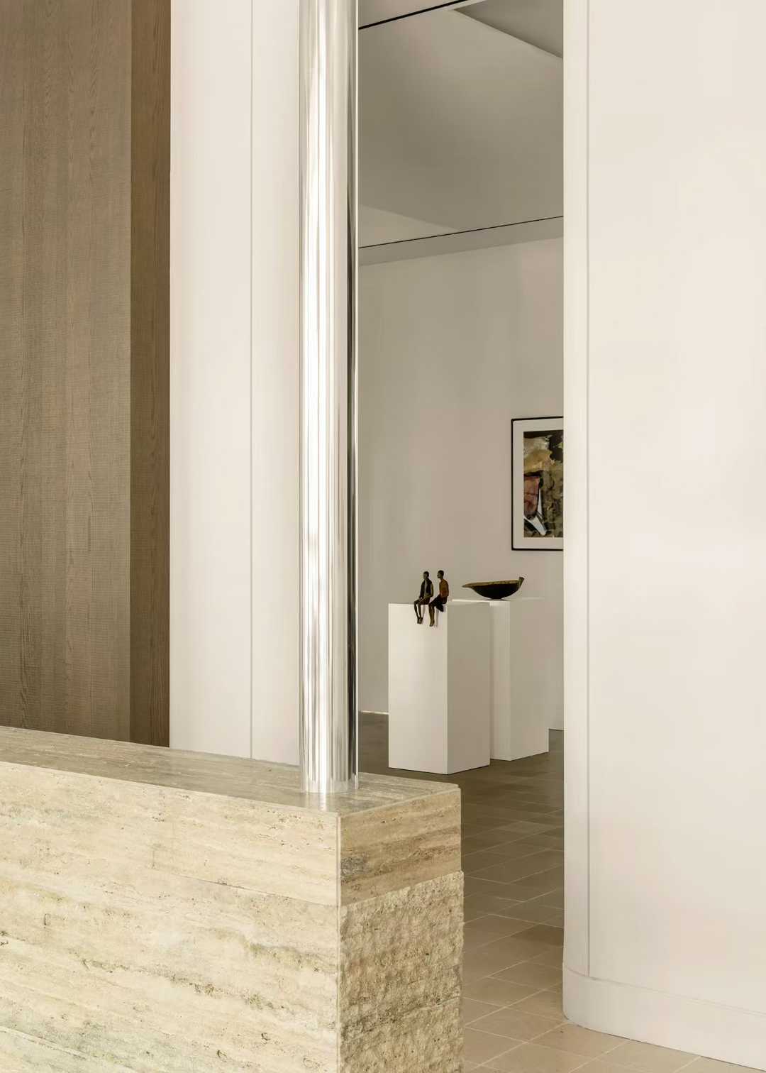 A travertine reception counter with a steel frame, in a white gallery interior