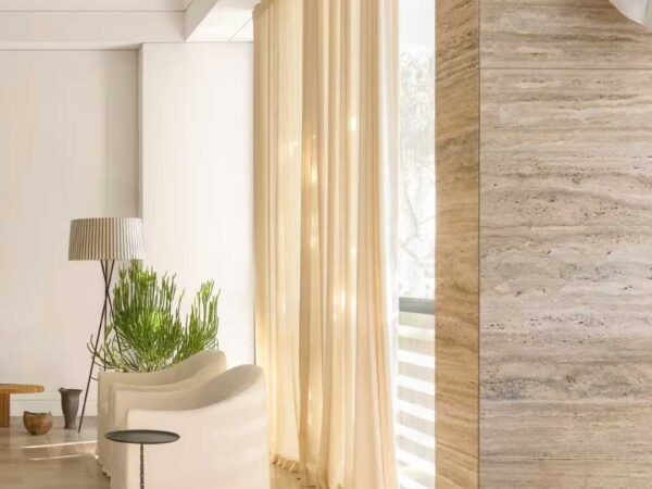 A travertine counter beside a timber chair and framed pictures on a white gallery wall