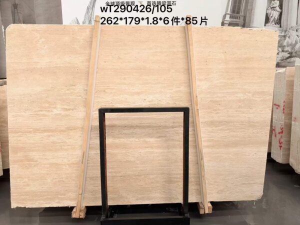 Rows of travertine slabs stored upright on timber racks inside a stone yard