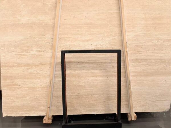 Rows of travertine slabs stored upright on timber racks, the cut faces toward the viewer